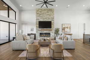 Living area with a high ceiling, hardwood / wood-style floors, a fireplace, and recessed lighting