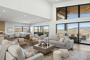 Living room with light wood-style flooring, a high ceiling, a mountain view, and recessed lighting