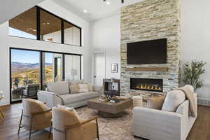 Living area with hardwood / wood-style floors, a stone fireplace, a high ceiling, a mountain view, and recessed lighting