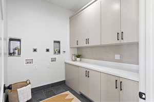 Laundry area featuring cabinet space, hookup for an electric dryer, dark stone finish floors, and washer hookup