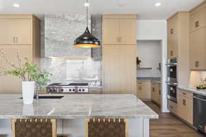 Kitchen with light brown cabinetry, light stone counters, dark wood-style flooring, stainless steel appliances, and recessed lighting