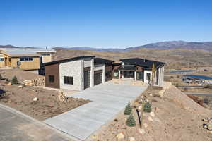 View of front of home with stone siding, a mountain view, driveway, and a garage