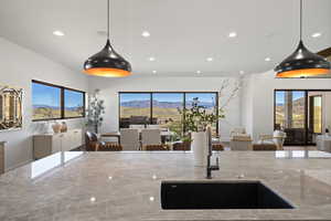 Kitchen featuring open floor plan, light stone countertops, hanging light fixtures, and recessed lighting