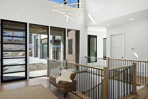 Hall with wood-type flooring, a high ceiling, recessed lighting, and an upstairs landing