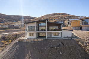 View of front of home with a mountain view, a balcony, a patio, and stone siding