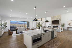 Kitchen featuring open floor plan, light stone counters, dark wood-type flooring, pendant lighting, and recessed lighting