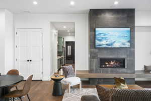Living room featuring dark wood-style floors, a tiled fireplace, and recessed lighting