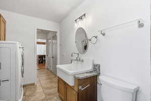 Half bathroom with vanity, washer / dryer, and light tile patterned flooring