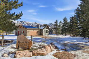 Rustic home with solar panels, a chimney, a mountain view, a metal roof, and an attached garage