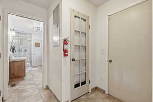 Corridor featuring light tile patterned flooring and electric panel