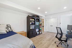 Bedroom featuring wood finished floors, an office area, recessed lighting, and a closet