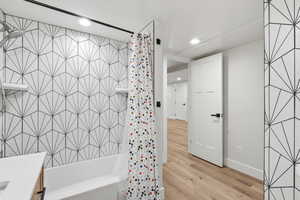 Full bathroom with shower / bath combo with shower curtain, light wood-style floors, vanity, and recessed lighting