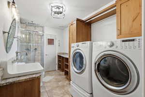 Laundry area featuring washing machine and clothes dryer and light tile patterned floors