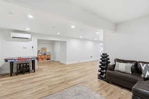 Living area featuring light wood-style flooring, recessed lighting, and a wall mounted air conditioner