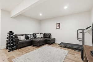 Living room featuring beam ceiling, light wood-style floors, and recessed lighting