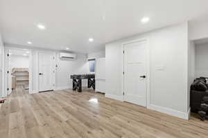 Interior space with recessed lighting, freestanding refrigerator, light wood-style flooring, and a wall mounted AC