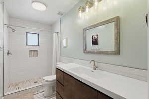 Full bath with vanity, a stall shower, tile walls, and light tile patterned flooring