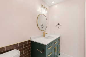 Half bath featuring vanity, tile walls, a wainscoted wall, and recessed lighting