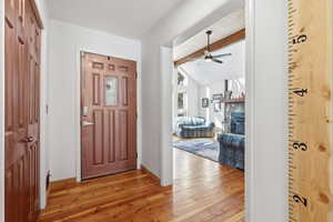 Entrance foyer with light wood finished floors, a ceiling fan, and a stone fireplace
