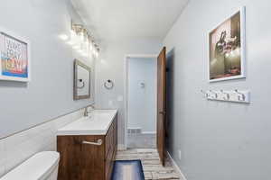 Half bath with vanity, light wood-type flooring, and tile walls
