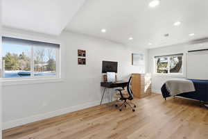 Bedroom with light wood-style floors, a desk, recessed lighting, and a wall mounted AC