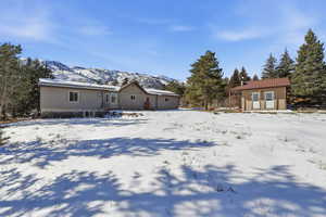 Snow covered back of property featuring backyard, a storage shed outbuilding and a mountain view