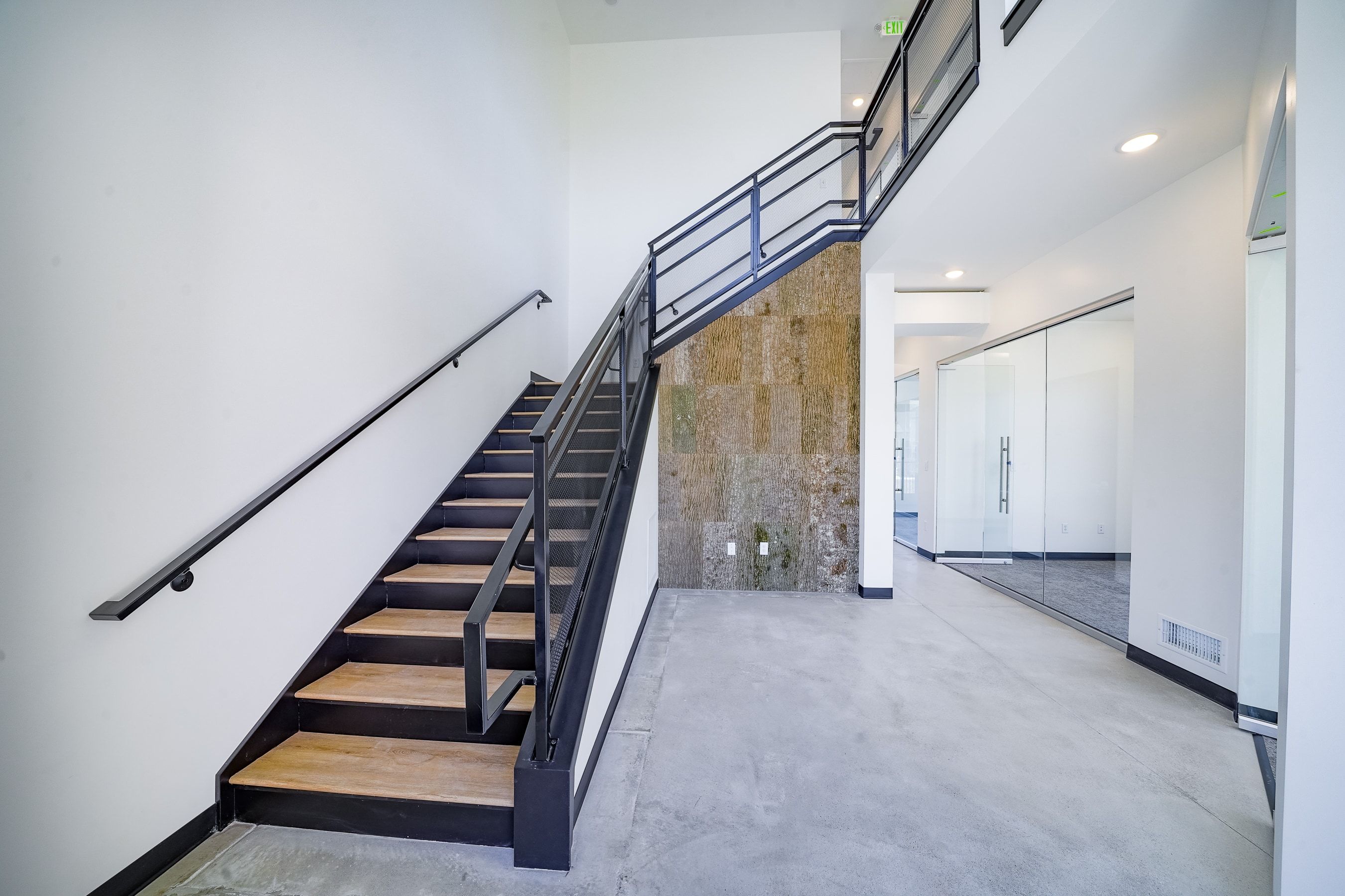 Stairway featuring a towering ceiling, concrete floors, and recessed lighting