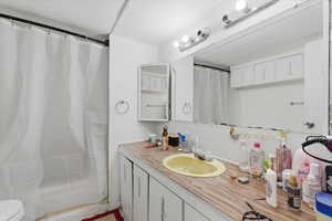 Full bath featuring vanity, curtained shower, and a textured ceiling