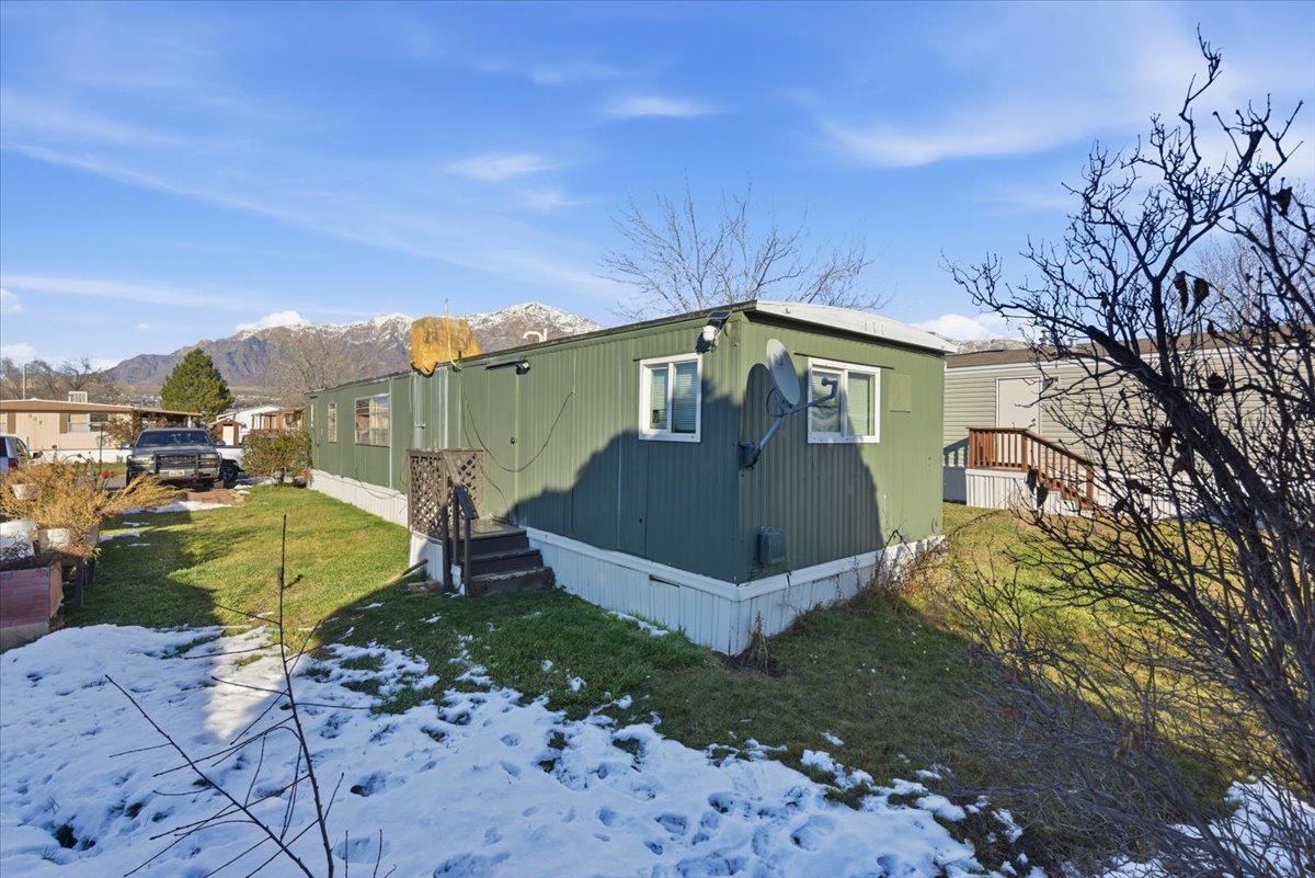 Snow covered property with a lawn and a mountain view