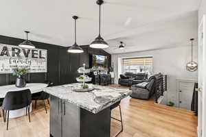 Kitchen featuring pendant lighting, a kitchen bar, a center island, light wood-type flooring, and a decorative wall