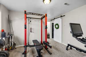 Workout area featuring carpet floors and a barn door