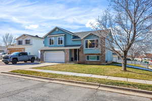 View of front of house featuring driveway, brick siding, roof with shingles, and a garage