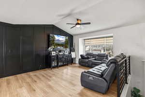 Living area with light wood finished floors, vaulted ceiling, and a ceiling fan