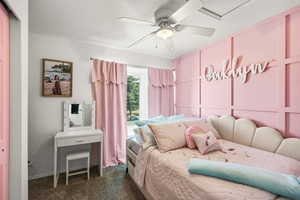 Bedroom with a decorative wall, dark carpet, ceiling fan, and a textured ceiling