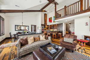 Living area with wood-type flooring, a chandelier, recessed lighting, high vaulted ceiling, and beamed ceiling
