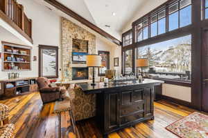 Bar featuring dark wood-type flooring, a fireplace, high vaulted ceiling, dark cabinets, and dark brown cabinetry