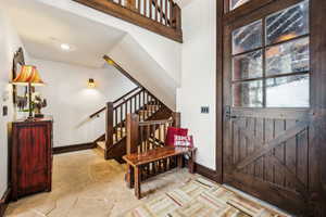 Foyer entrance featuring light stone finish flooring and stairs