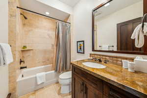 Full bathroom with shower / bath combo, vanity, tasteful backsplash, and light tile patterned flooring