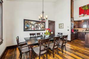 Dining space featuring dark wood finished floors, a chandelier, and a towering ceiling