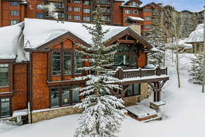 Snow covered house featuring stone siding
