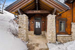View of exterior entry with stone siding and covered porch