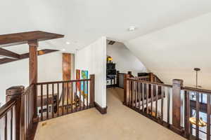 Corridor featuring an upstairs landing, carpet, and lofted ceiling