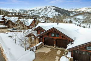 View of front of house featuring a mountain view, driveway, a garage, and stone siding