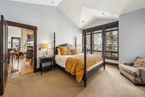 Carpeted bedroom with vaulted ceiling and baseboards