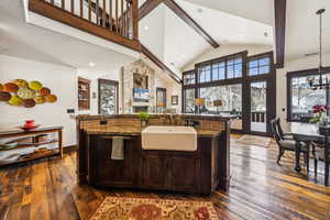 Kitchen with dark brown cabinetry, dark wood-style flooring, a fireplace, beamed ceiling, and high vaulted ceiling