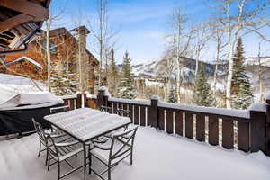 Snow covered deck with outdoor dining space and a mountain view