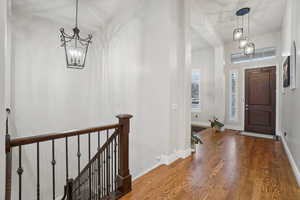 Entryway with wood finished floors and a chandelier
