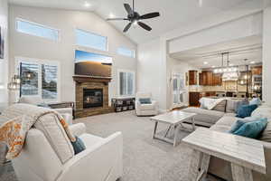 Carpeted living room with recessed lighting, a ceiling fan, a stone fireplace, and high vaulted ceiling