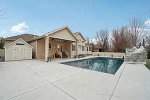View of pool featuring a shed, a patio area, and a fenced backyard