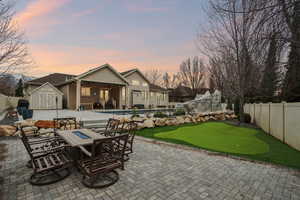 Patio terrace at dusk with a fenced backyard, an area to practice putting, a patio area, a storage shed, and area for grilling